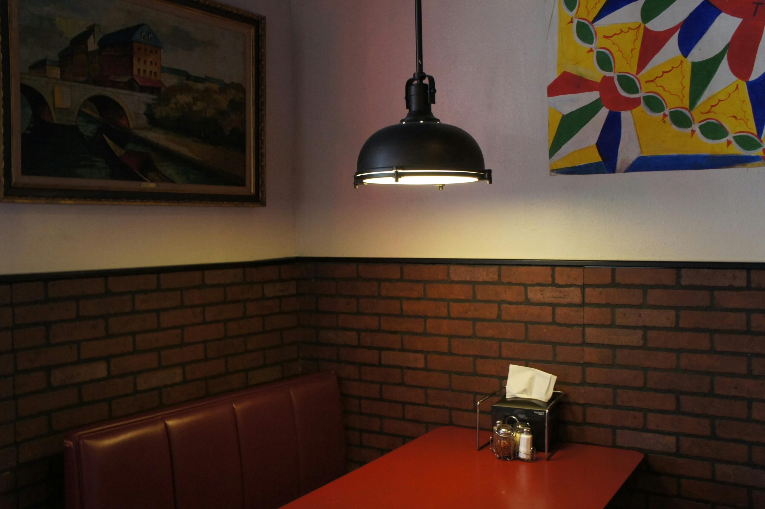 A cozy restaurant booth with a red table, brick walls, and modern lighting in South Charleston.